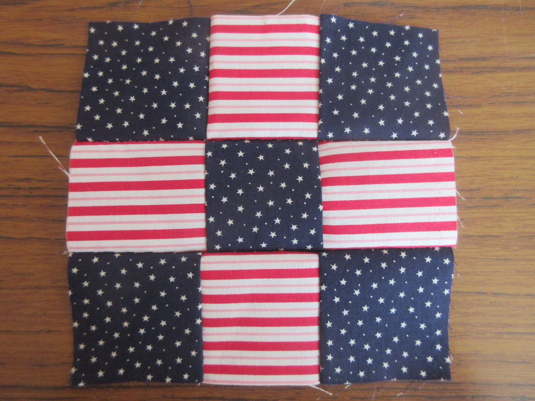 9 squares of fabric sewn in a grid formation.  The centre and corner squares are navy blue with white stars.  The other 4 squares are red and white striped.