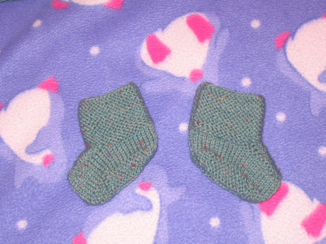 Green knitted baby booties.  These match the hooded jumper above.