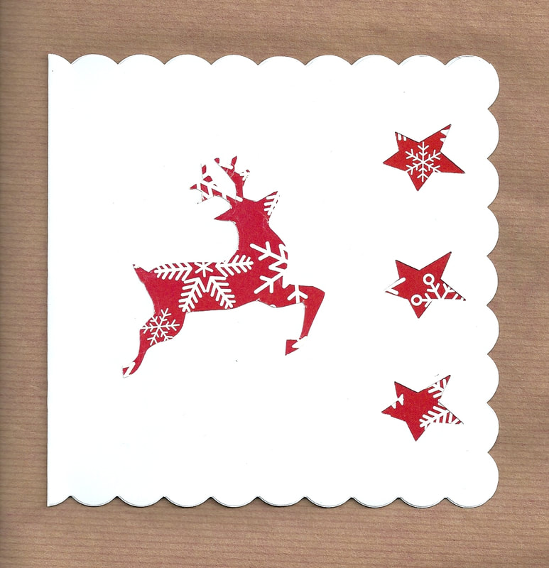 Scan of a white card with scalloped edges.  There is a reindeer and 3 stars on it, all made from red paper with a snowflake pattern.